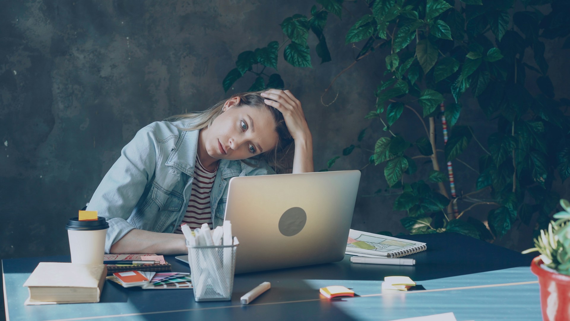 Woman sitting at desk with laptop in NYC looking exhausted and overwhelmed by high-functioning anxiety