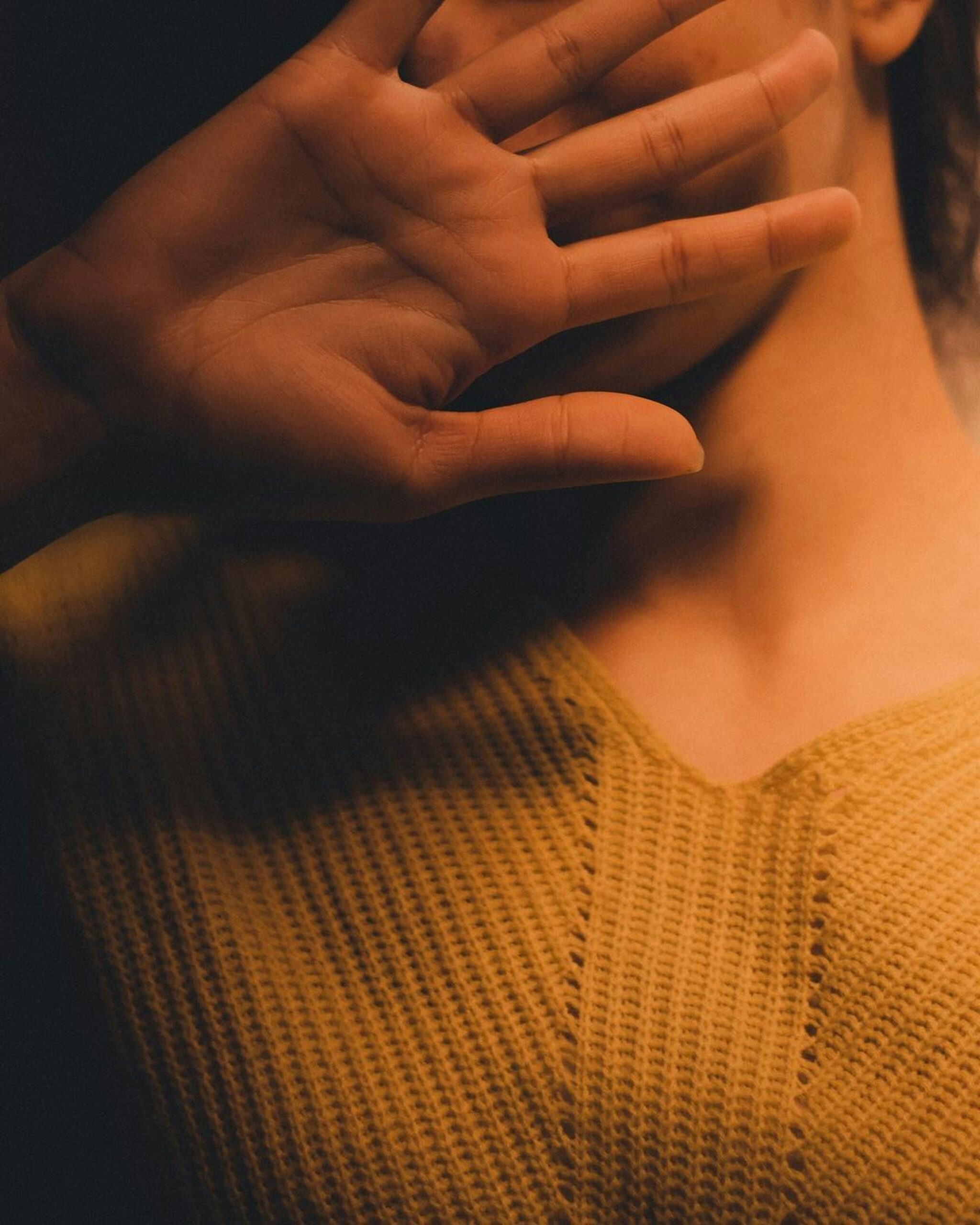Person gently raising hand to light, symbolizing somatic awareness and mindful embodiment