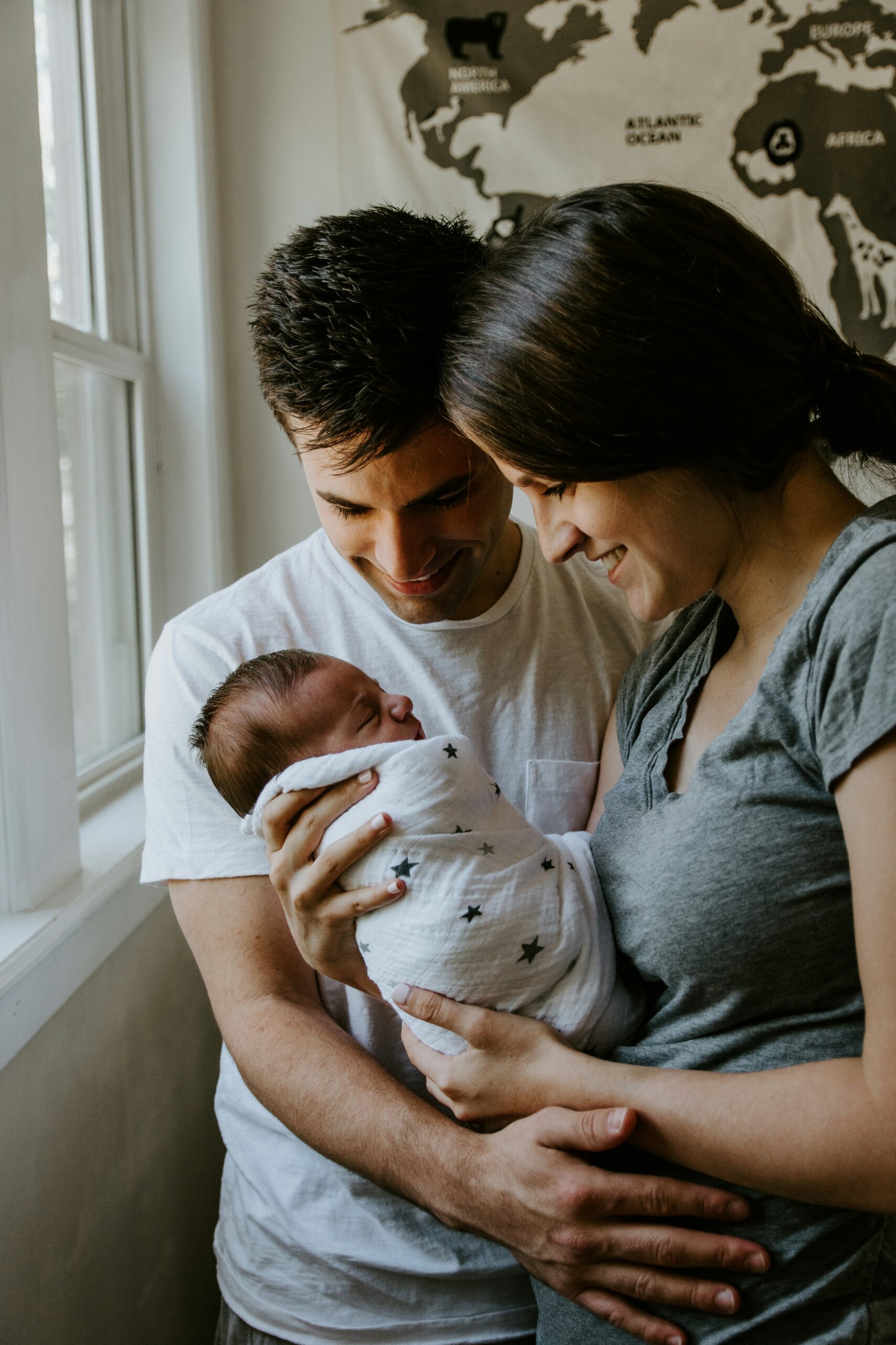Parents holding newborn in natural light during somatic therapy for new parents in NYC