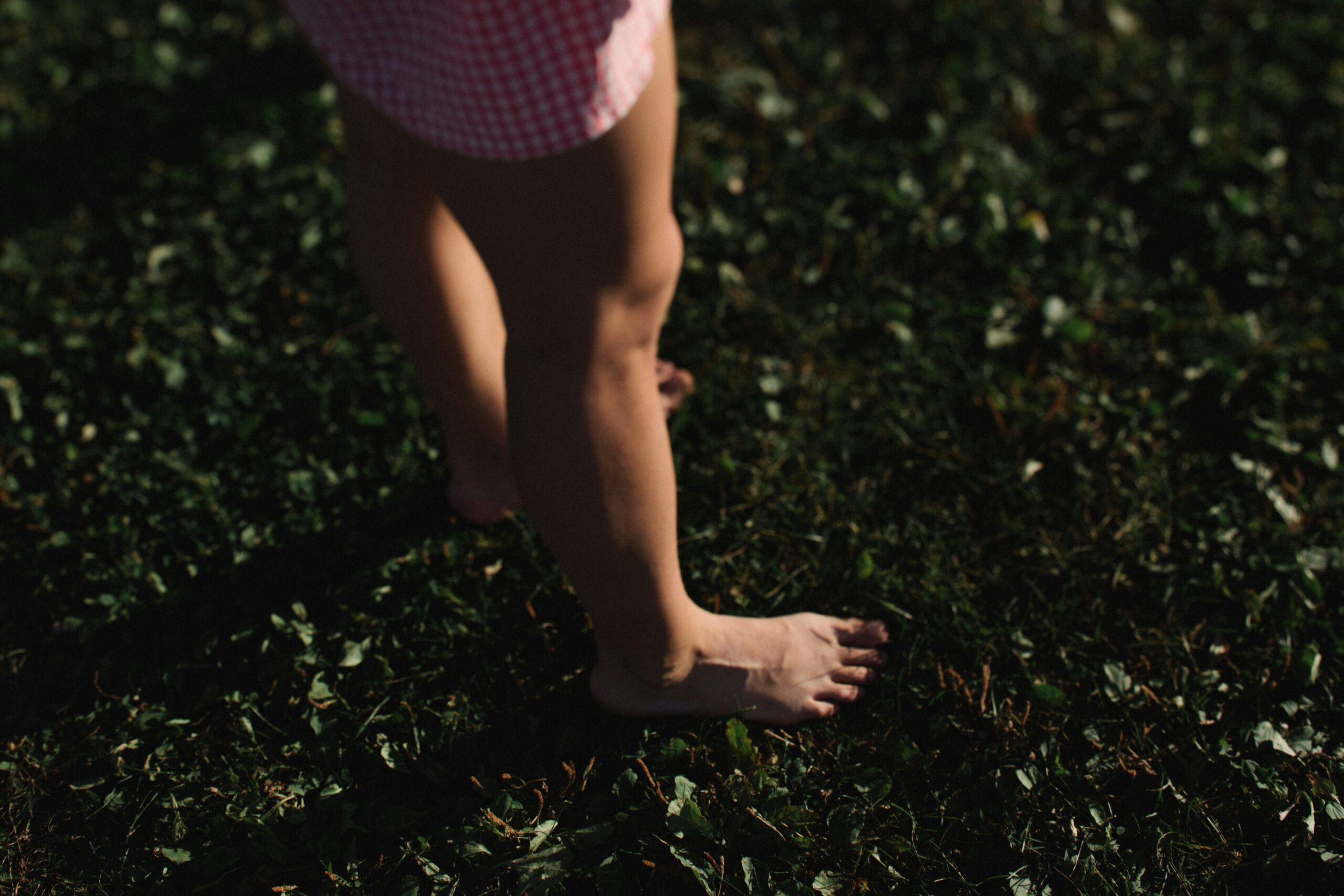 Person standing barefoot on grass to practice grounding techniques and reconnect with the body in nature.