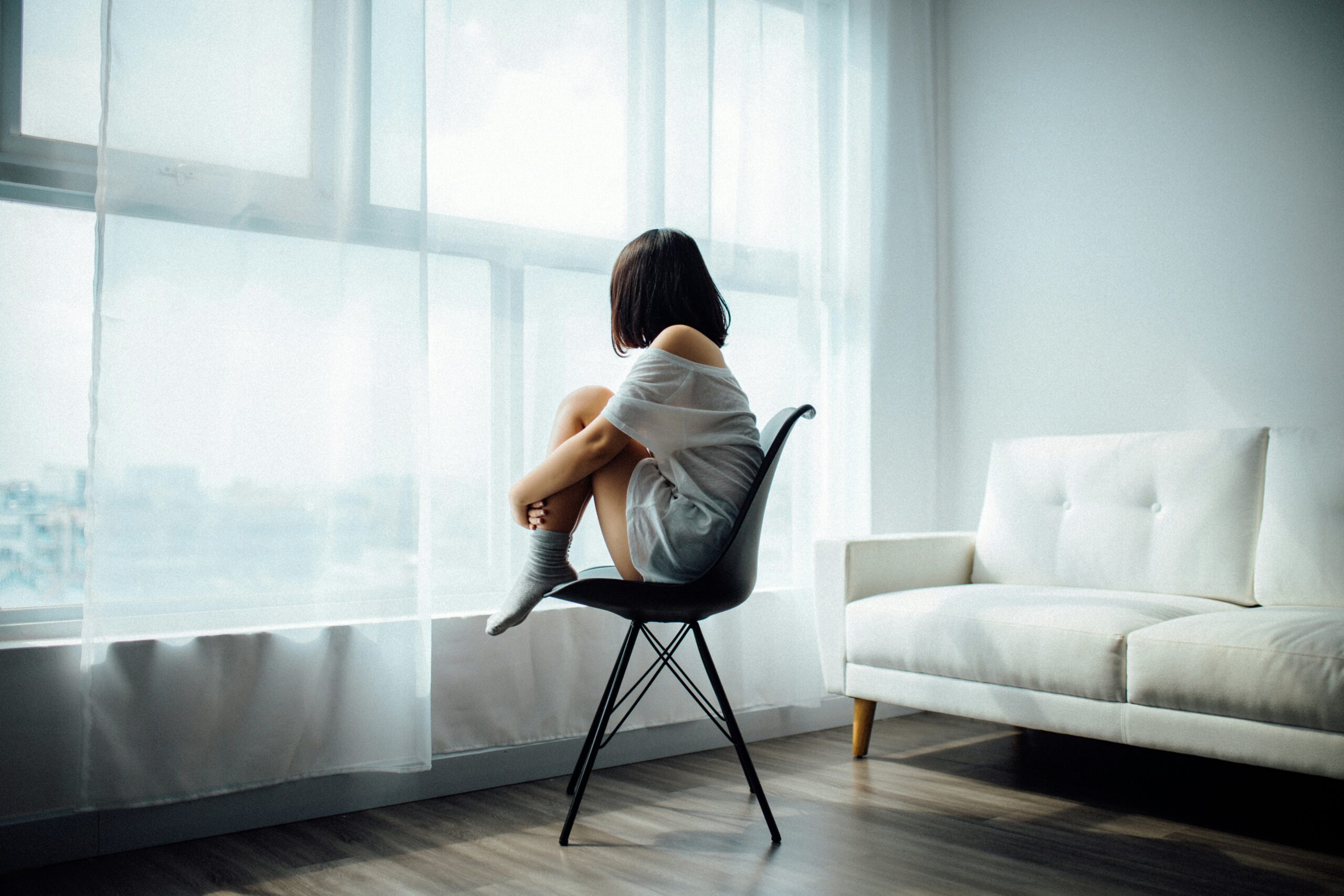 Woman sitting quietly by a window reflecting on her feelings during somatic therapy for depression