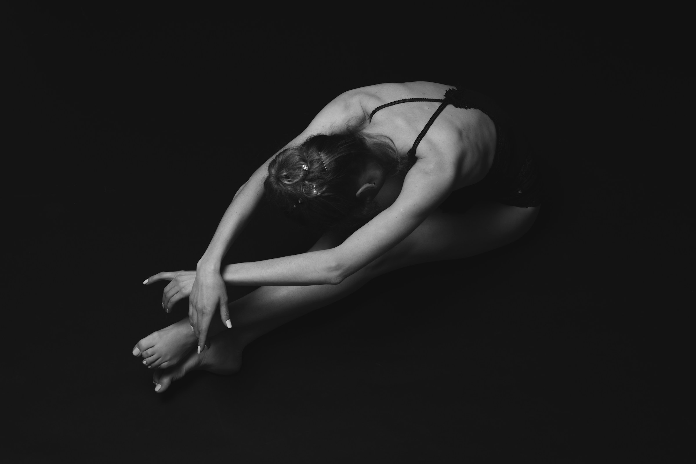 Woman seated in a folded posture on the floor representing trauma and body awareness in somatic therapy