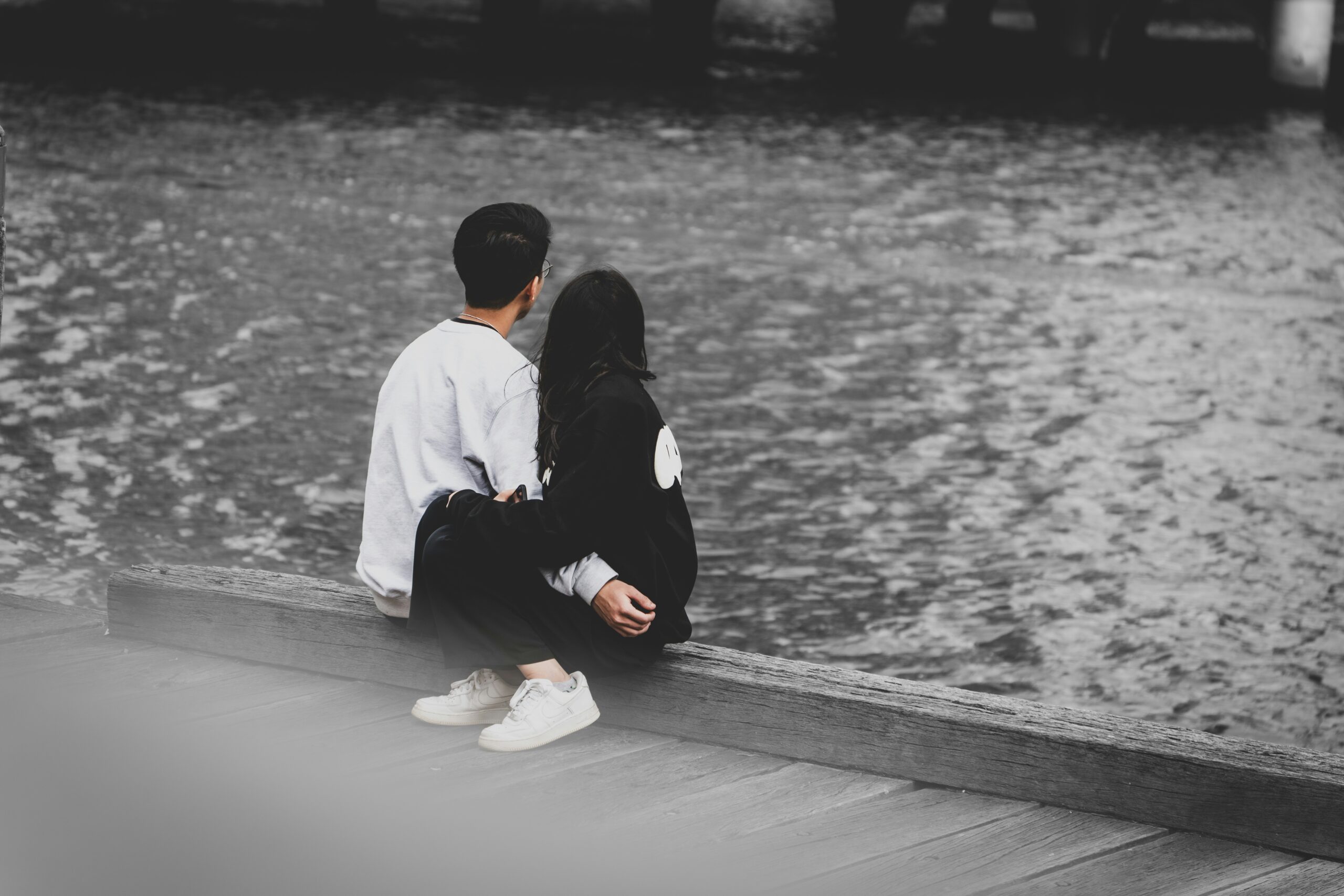 Couple sitting closely together by the water offering emotional support during a fertility journey