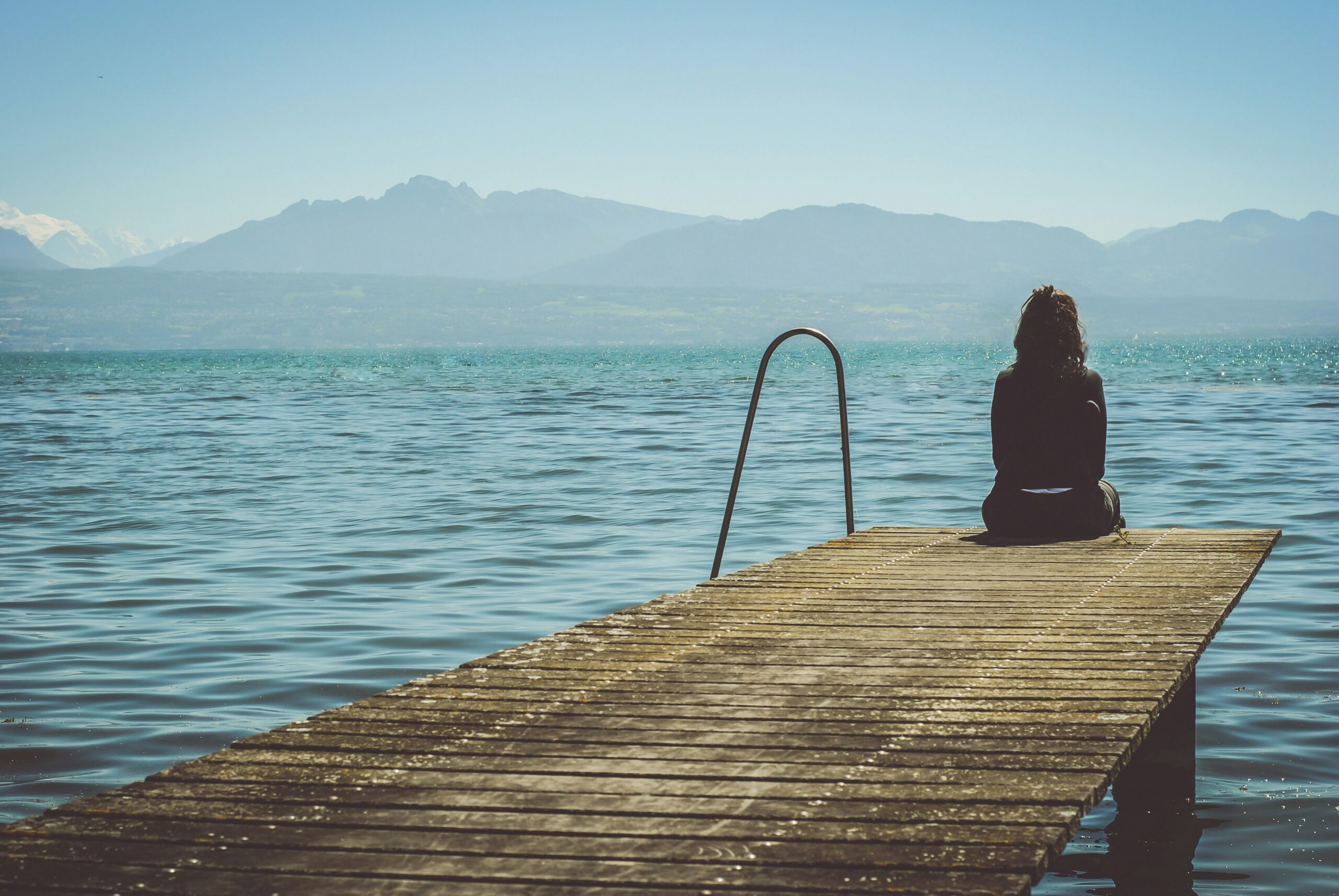 Person sitting on a dock by a calm lake reflecting; ketamine-assisted therapy for depression in NYC